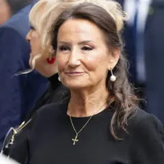 Paloma Rocasolano, con pendientes de perla y un collar con cruz, sonríe con elegancia.
