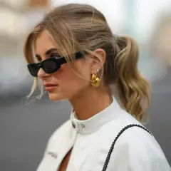 Mujer con coleta y gafas de sol, luciendo un corte de pelo con flequillo cortina que enmarca su rostro.