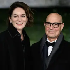 Felicity Blunt y Stanley Tucci sonríen a la cámara, vestidos elegantemente para un evento.