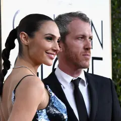 Yaron Varsano y su esposa, Gal Gadot, posan sonrientes en la alfombra dorada.