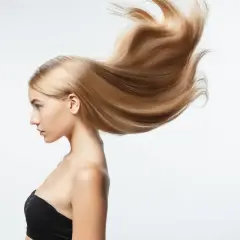 Perfil de mujer con pelo largo rubio y sedoso que se mueve con el viento.
