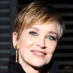 Mujer de 60 años con cortes de pelo corto modernos, luciendo un pendiente dorado y una sonrisa radiante.