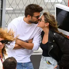 Piqué y Clara Chía se besan apasionadamente, ajenos a la mujer con pelo rizado y gafas de sol que les mira de reojo.