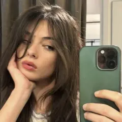 Deva Cassel se toma un selfie con su teléfono, apoyando la barbilla en la mano.