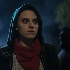 Jone Laspiur, con capucha y pañuelo rojo, mira con intensidad en la noche.