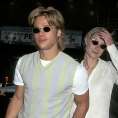 Brad Pitt joven con gafas de sol y un suéter a rayas, junto a una mujer rubia.