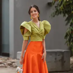 Elegante look invitada boda otoño: top verde con volantes y falda naranja.