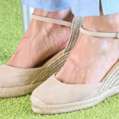 Alpargatas de cuña color camel, con tiras al tobillo, similares a las que usa la reina Letizia, sobre una alfombra verde.