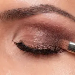 Aplicando sombra marrón con brocha. Aprende como maquillar los ojos a partir de los 50 años para un look elegante y natural.