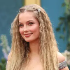Hannah Dodd, con cabello rubio ondulado y adornos florales, sonríe con un vestido plateado.