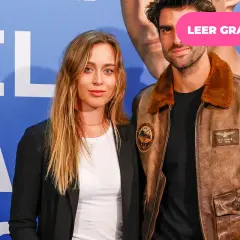 Paula Badosa y su novio posan sonrientes ante un fondo azul con letras blancas.
