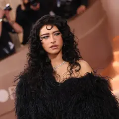 Odessa A'zion, con su cabello rizado y oscuro, luce un elegante vestido negro de plumas y un collar de diamantes.