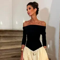 Inés Domecq posa con un elegante vestido negro de escote Bardot y falda voluminosa color crema, luciendo joyas doradas.