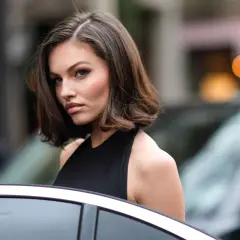Mujer con corte bob asimétrico, ideal para cortes de pelo para cara redonda, luciendo elegante junto a un coche.