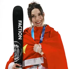 Eileen Gu, sonriente y envuelta en la bandera china, sostiene un esquí Faction.