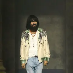 Alessandro Michele, con su icónico estilo, luce una chaqueta bordada y jeans.