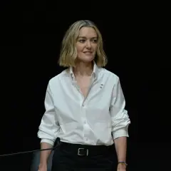 Marta Ortega Pérez, con una camisa blanca y un micrófono, sonríe ante la cámara.