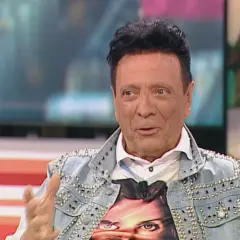 Rupert, el peluquero, luce una chaqueta vaquera tachonada y una camiseta con un rostro.