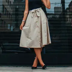 Mujer con falda beige abotonada y lazo, mostrando diferentes tipos de faldas para un look casual chic.