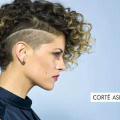 Mujer con pelo corto rizado y rapado asimétrico, luciendo un estilo audaz y moderno.