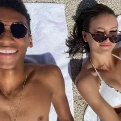 Felix Auger-Aliassime y su novia disfrutan del sol en la playa. Él sonríe a la cámara, ella se ajusta las gafas de sol.
