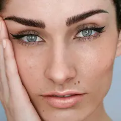 Rostro de mujer con microblading cejas perfectas, delineado de ojos y piel con pecas.