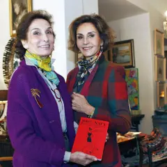 Naty Abascal y otra mujer posan con un libro rojo titulado "100% NATY".