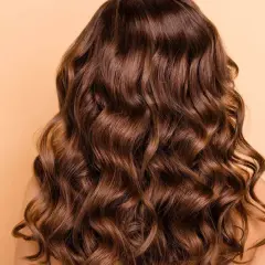 Cabello castaño con ondas naturales, un look de permanente ondulada que irradia brillo y movimiento.