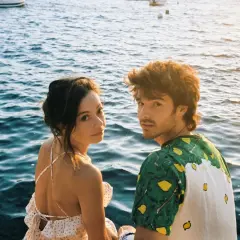 Anna Castillo y Álvaro Mel disfrutan de un atardecer junto al mar, con barcos al fondo.