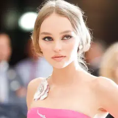 Lily-Rose Depp, con un vestido rosa y maquillaje dramático, posa con elegancia.