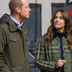 William van Wales y Kate Middleton, ambos con chaquetas, conversan frente a un mural.