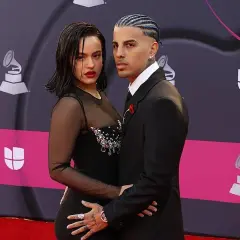 Rosalía y su novio, Rauw Alejandro, posan juntos en la alfombra roja. Ella luce un vestido negro con transparencias y pedrería, él un traje elegante.
