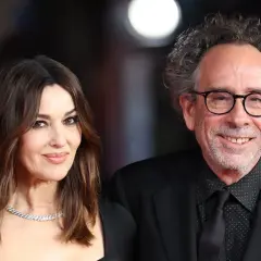 Monica Bellucci y Tim Burton, una pareja que parece sacada de una película de fantasía gótica, posan juntos con elegancia.