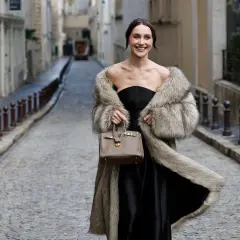 Elegante mujer con abrigo de pelo y bolso, lista para una boda en invierno.