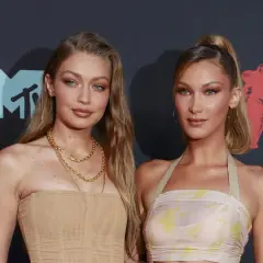 Alana Hadid y su hermana Bella posan juntas en la alfombra roja, luciendo atuendos elegantes y maquillaje impecable.
