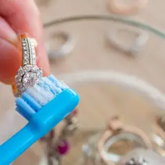 Limpia joyas con un cepillo de dientes azul y jabón.