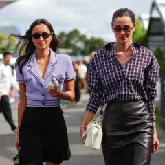 Rebecca Donaldson y su amiga pasean con estilo. Una lleva un blazer lila y falda negra, la otra, camisa a cuadros y falda de cuero.