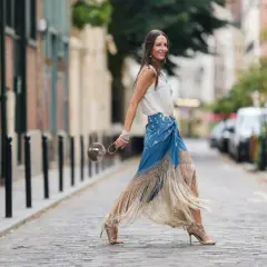 Mujer con falda larga de flecos y top blanco, lista para la feria de abril sin vestido.