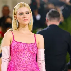Nicola Peltz deslumbra con un vestido rosa vibrante y guantes a juego, luciendo elegante y radiante.