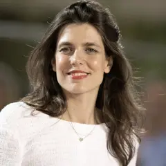 Charlotte Casiraghi sonríe con un collar delicado y un suéter blanco.
