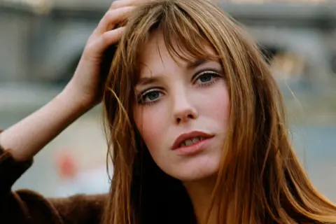 La it girl con su mano en el pelo, mirada intensa y labios entreabiertos, irradia un estilo icónico.