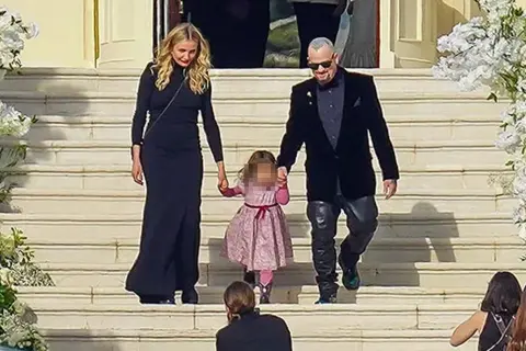 Cameron Diaz camina de la mano con su hija y su esposo por unas escaleras adornadas con flores.
