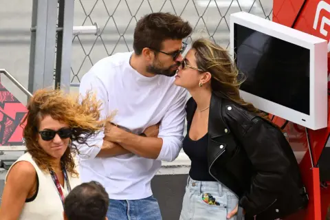 Piqué y Clara Chía se besan apasionadamente, ajenos a la mujer con pelo rizado y gafas de sol que les mira de reojo.