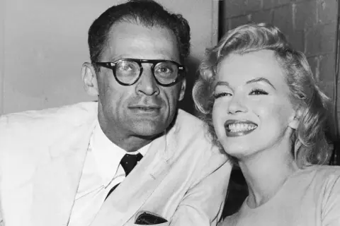 Marilyn Monroe sonríe junto a su cónyuge, Arthur Miller, un dramaturgo con gafas.