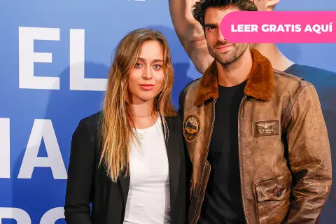 Paula Badosa y su novio posan sonrientes ante un fondo azul con letras blancas.