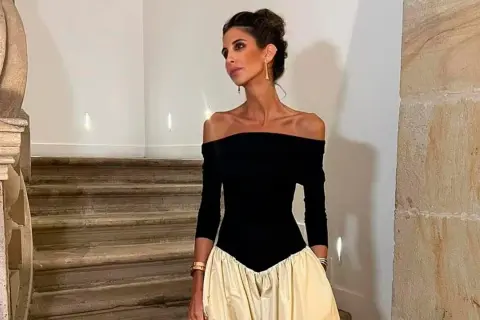 Inés Domecq posa con un elegante vestido negro de escote Bardot y falda voluminosa color crema, luciendo joyas doradas.