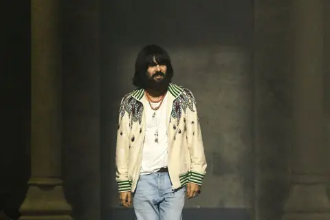 Alessandro Michele, con su icónico estilo, luce una chaqueta bordada y jeans.