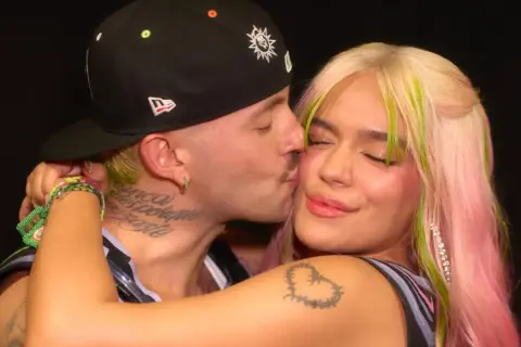 Feid le da un tierno beso a Karol G, capturando un momento íntimo entre los artistas.