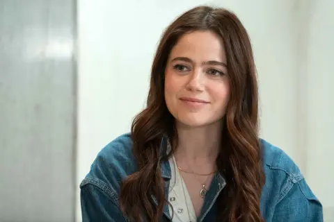 Molly Gordon, con su cabello castaño suelto y una chaqueta vaquera, sonríe con dulzura.