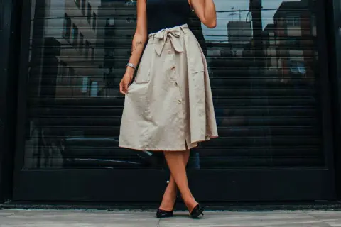 Mujer con falda beige abotonada y lazo, mostrando diferentes tipos de faldas para un look casual chic.